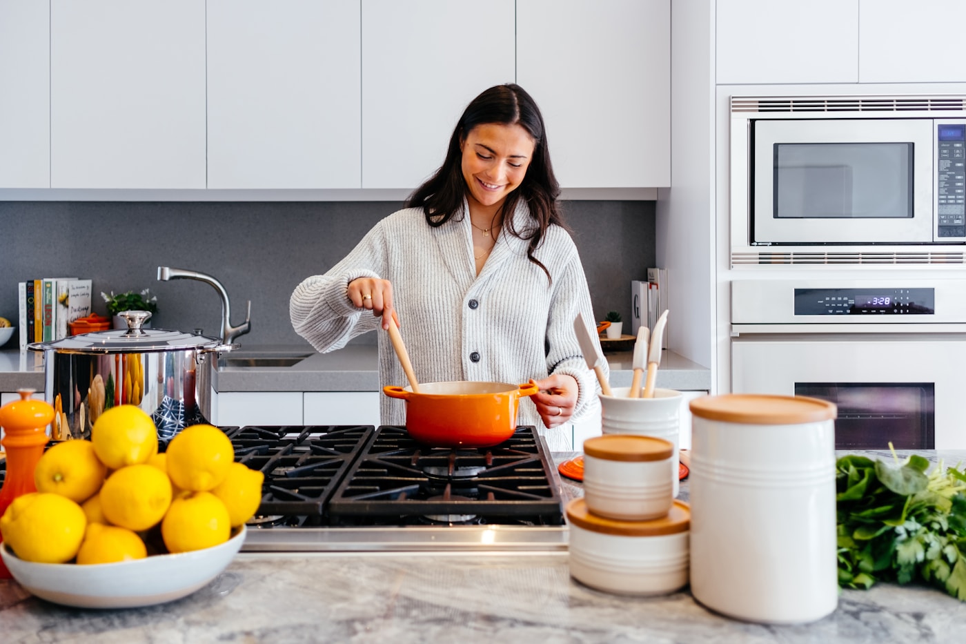 Person cooking in a bright modern modular kitchen with white cabinetry